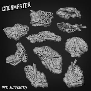 May include: A selection of grey, 3D-printed botanical elements, featuring diverse leaf shapes and textures. The text "GOONMASTER" and "PRE-SUPPORTED" are visible. These elements are designed for crafting or decorative use.