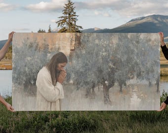 May include: An art print depicting a figure in a white robe with hands clasped in prayer. The background features a muted landscape with trees and a mountain range, with a color palette of beige, gray, and blue.
