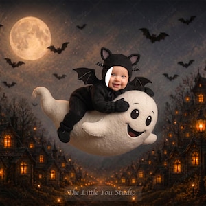 May include: A baby wearing a black bat costume with ears and wings, riding a large white plush ghost. The background features a dark night scene with a full moon, flying bats, and a village of illuminated houses. Text reads The Little You Studio.