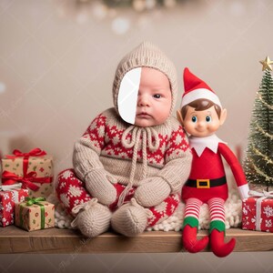 Può includere: Un bambino in un completo di maglia a fantasia rossa e bianca e cappello abbinato è seduto accanto a una bambola elfo rossa e bianca e un piccolo albero di Natale. Diversi regali confezionati sono in primo piano.