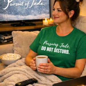 May include: A green short-sleeved t-shirt featuring the white printed text Pursuing Jade. DO NOT DISTURB. The shirt has a crew neckline and is made of a solid-colored fabric. The design is centered on the chest area of the garment.