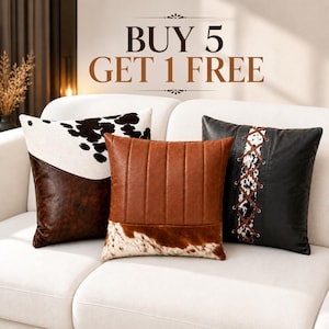 May include: Three square throw pillows featuring cowhide and faux leather textures. The left pillow has a white and black cowhide top with a brown base. The centre pillow is brown with vertical stitching and a cowhide bottom. The right pillow is black with a central cowhide panel and brown lace-up detailing. Text reads BUY 5 GET 1 FREE.