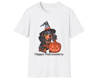 May include: A white short-sleeved t-shirt featuring a graphic of a black and tan dachshund wearing a grey witch hat. Next to the dog is an orange jack-o'-lantern pumpkin. Below the graphic, the text reads Happy Halloweeny in black letters.