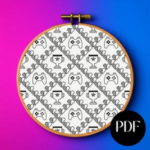 May include: A cross-stitch embroidery hoop featuring a repeating pattern of video game controllers, trophies, and hearts in black and white. The wooden hoop is set against a gradient background of purple and blue. A black circle with the letters "PDF" is in the lower right corner.