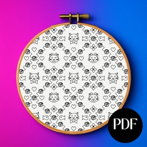 May include: A cross-stitch pattern with a repeating design of cat faces, hearts, and fish in black on a white background. The design is set within a wooden embroidery hoop. A PDF icon is in the lower right corner.