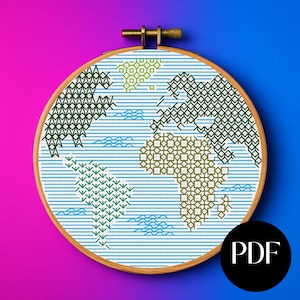 May include: A cross-stitch embroidery hoop with a world map design. The continents are in green and tan geometric patterns against a blue and white striped background. The wooden hoop has a brass adjustment screw. A black circle with the letters "PDF" is in the lower right corner.