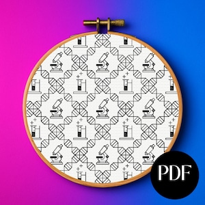 May include: A cross-stitch embroidery hoop with a science-themed design. The pattern features black and white illustrations of microscopes, beakers, and DNA strands. The wooden hoop has a PDF icon in the bottom right corner.