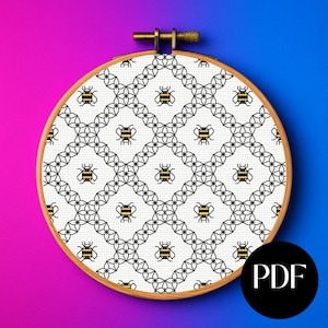 May include: A cross-stitch embroidery hoop featuring a repeating pattern of bees and geometric shapes in black and yellow on a white background. The wooden hoop is round, and the background is a gradient of pink and blue. A black circle with the letters "PDF" is in the lower right corner.