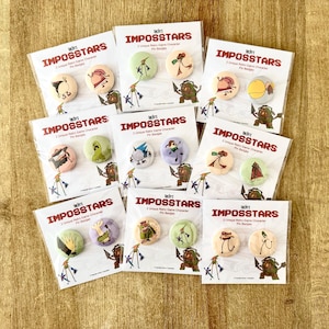 Puede incluir: Una colección de insignias "Imposstars", cada tarjeta con dos diseños únicos de personajes de juegos retro. Los pines son redondos con ilustraciones coloridas, y las tarjetas tienen el logotipo y el texto "Imposstars".