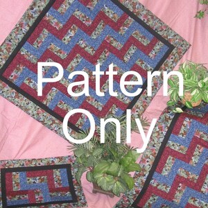 Op de afbeelding: Drie gestikte vierkante stoffen met een zwarte rand en een zigzagpatroon in tinten blauw en bordeauxrood. De vierkanten zijn gerangschikt op een roze oppervlak. De tekst "Pattern Only" is in wit op het grootste vierkant gedrukt.