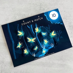 May include: A dark blue educational game with the text "COUNT & MATCH" and the number "10". The game features illustrations of glowing yellow butterflies. The butterflies are scattered across a dark blue background.