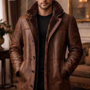May include: A brown leather coat with a fur-lined collar and button closure. The coat has a classic design with pockets and a tailored fit. The image features the "PLANIO LEATHER" logo in a circular design.