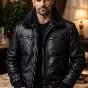 Peut inclure: Veste en cuir noir avec un col en fausse fourrure noire. La veste a une fermeture éclair sur le devant, plusieurs poches et des poignets côtelés. La veste est de Planio Leather, comme on le voit sur le logo.