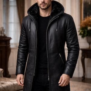 May include: A black leather hooded coat with a fur-lined hood. The coat has a zipper closure, long sleeves, and a tailored fit. The coat is from Planio Leather, as indicated by the logo on the top left.