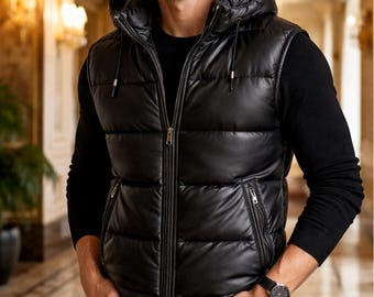 Può includere: Un gilet nero trapuntato con cappuccio, cerniera frontale, tasche laterali e una camicia nera a maniche lunghe sotto. Il gilet è indossato con jeans neri e un orologio. L'immagine include il testo "PLANIO LEATHER" in un logo circolare.