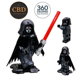 May include: Black custom brick design figure with a red lightsaber. The figure has a black helmet and cape. The figure is standing on a black base. The image also includes the text "CBD Custom Brick Design" and "360 Degree Pad Printing".