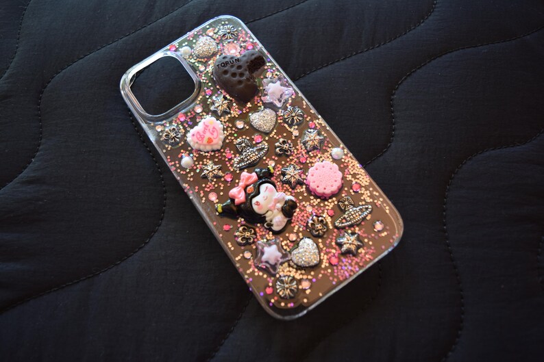 Puede incluir: Funda de tel&eacute;fono transparente decorada con varios abalorios, incluyendo corazones, estrellas y una figura de Minnie Mouse. La funda tiene un fondo brillante con acentos rosas y plateados. La funda est&aacute; dise&ntilde;ada para un tel&eacute;fono.