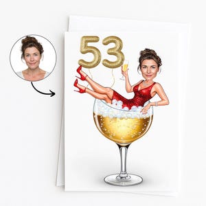 May include: A birthday card with a cartoon illustration of a woman in a red dress and heels relaxing in a large wine glass filled with champagne. Gold number balloons spell out "53". A small portrait of the woman is in the upper left corner.