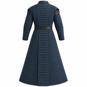 May include: A long, dark blue coat featuring a high collar, quilted vertical paneling on the back and sleeves, and a black belt at the waist. The shoulders are accented with black leather-like detailing and lacing, creating a structured appearance.