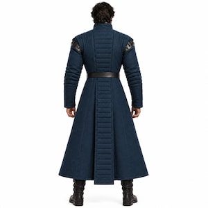 May include: A long, dark blue coat featuring a high collar, quilted vertical paneling on the back and sleeves, and a dark brown belt at the waist. The garment has structured shoulders with dark leather-like accents and reaches the mid-calf.