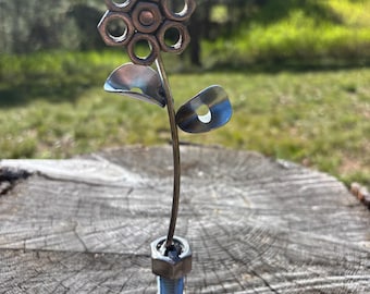 ナットとボルトのポットにワッシャーの葉が付いた金属製の花。