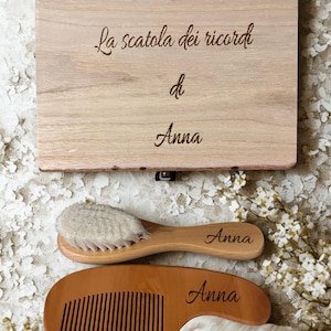 May include: A wooden keepsake box with the inscription "La scatola dei ricordi di Anna" is displayed with a wooden brush and comb, each engraved with "Anna". The brush has soft bristles.