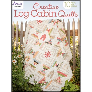 May include: A book titled "Creative Log Cabin Quilts" by Annie's Quilting featuring 10 fresh new designs. The cover shows a colorful log cabin quilt with a white background and a wooden fence in the background.