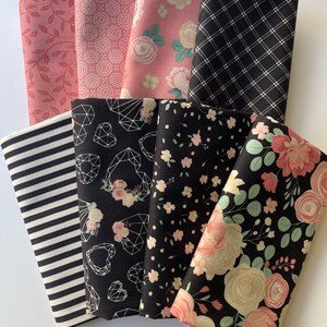 May include: A set of eight fabric squares in pink and black floral patterns. The fabrics feature geometric designs, stripes, and floral motifs.