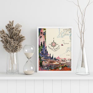 Pu&ograve; includere: Una stampa incorniciata di una mappa della Terra di Mezzo, con una rosa dei venti e illustrazioni dettagliate di paesaggi. L'opera d'arte &egrave; in una cornice bianca ed &egrave; esposta su una mensola bianca.