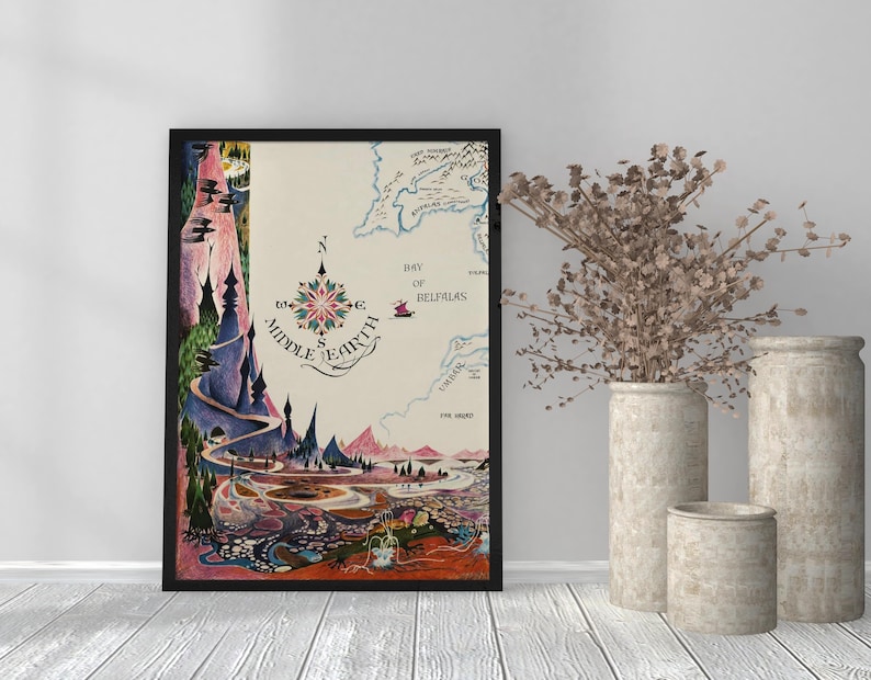Pu&ograve; includere: Una stampa artistica incorniciata di una mappa della Terra di Mezzo. La mappa presenta una rosa dei venti e illustrazioni dettagliate di paesaggi, montagne e specchi d'acqua. La tavolozza dei colori include sfumature di blu, verde, rosa e marrone. La stampa &egrave; esposta con vasi decorativi.