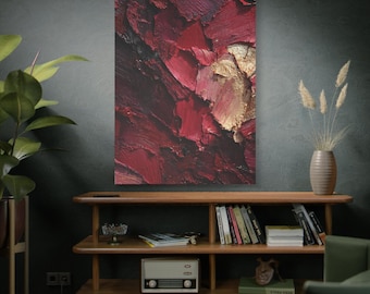 Könnte beinhalten: Abstrakte Leinwandkunst mit Nahaufnahme von strukturierten Pinselstrichen in Rot- und Goldtönen. Das Kunstwerk hängt an einer Wand über einem Holzregal mit Büchern und Ornamenten. Das Bild deutet auf ein Thema der Wohnkultur hin.