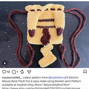 May include: A yellow and brown crochet drawstring backpack featuring a square body with horizontal brown stripes, two thick brown braided straps, and a prominent zigzag-shaped tail attached to the center of the front panel.