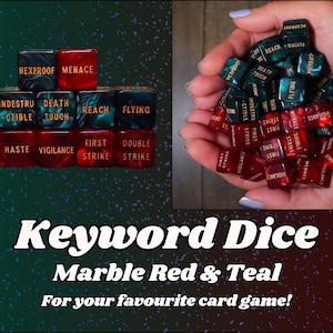 May include: Keyword dice in marble red and teal. The dice feature various game-related keywords in gold lettering. The image includes a pile of dice held in hands and a stacked arrangement of dice.
