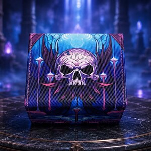 May include: A square deck box featuring a vibrant blue and purple graphic print of a stylised skull with wing-like accents. The design includes intricate geometric lines and pointed shapes, with a textured surface finish on the exterior panels.