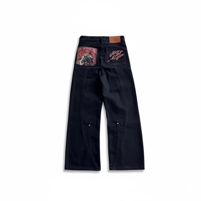 Puede incluir: Vaqueros de mezclilla azul oscuro con dise&ntilde;o de pernera ancha. Los bolsillos traseros presentan un estampado gr&aacute;fico rojo y negro y un logotipo estilizado. Los vaqueros tienen costuras decorativas y un parche de cuero.