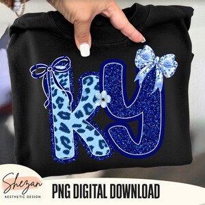 May include: Black sweatshirt featuring the letters "KY" in blue. The "K" has a light blue leopard print design, while the "Y" is a glittery blue. Decorative bows and a small flower accent the design. The text "PNG DIGITAL DOWNLOAD" is at the bottom.