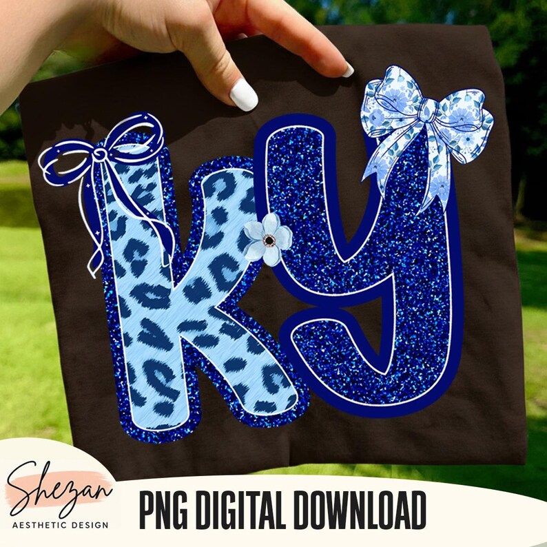 May include: A brown background with the letters "KY" in blue. The letter "K" has a light blue leopard print pattern, and the letter "Y" is a glittery blue. A blue bow and a small white flower are also present.