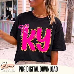 May include: Black t-shirt featuring a large pink "KY" graphic with a leopard print outline. A pink bow and small flower embellish the design. The text "PNG DIGITAL DOWNLOAD" is visible.