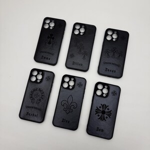May include: Black phone cases with various engraved designs, including crosses, fleur-de-lis, and the words "Chrome Hearts." Some cases feature personalized names like "Emma," "Dillon," "Susan," "Rachel," "Elsa," and "Sam."