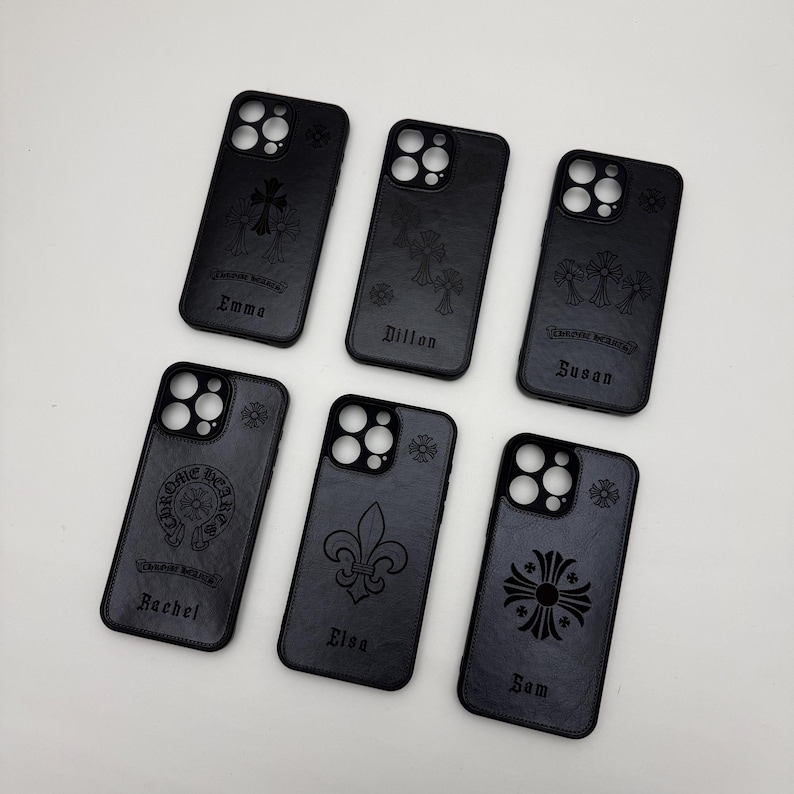 May include: Black phone cases with various engraved designs, including crosses, fleur-de-lis, and the words "Chrome Hearts." Some cases feature personalized names like "Emma," "Dillon," "Susan," "Rachel," "Elsa," and "Sam."