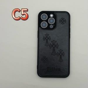 May include: Black phone case with a cross design. The case has a black border and a textured back with embossed crosses and the word "Dillon". The case also has a camera cutout and the text "C5" in a red and orange font.