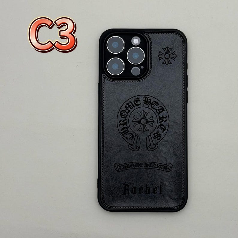 May include: Black leather phone case with embossed Chrome Hearts logo and the name "Rachel". The case has a stitched border and a camera cutout. A red and orange "C3" sticker is in the upper left corner.