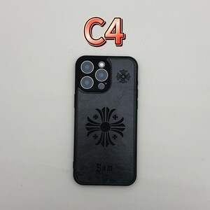 Pu&ograve; includere: Custodia per telefono nera con un design a croce decorativo e la parola "Sam" in basso. La custodia ha un aspetto strutturato e un piccolo design a croce vicino alla fotocamera. Il testo "C4" &egrave; in alto.