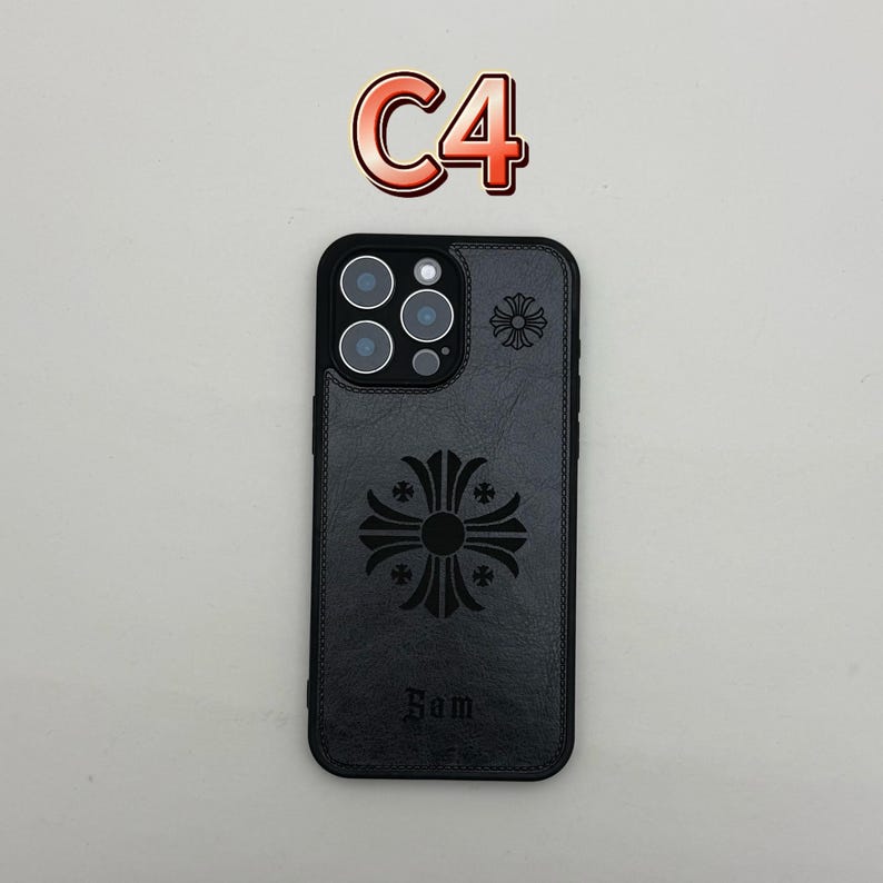 Pu&ograve; includere: Custodia per telefono nera con un design a croce decorativo e la parola "Sam" in basso. La custodia ha un aspetto strutturato e un piccolo design a croce vicino alla fotocamera. Il testo "C4" &egrave; in alto.