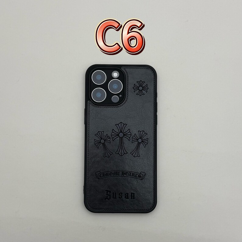 Pu&ograve; includere: Custodia per telefono in pelle nera con disegni a croce in rilievo e la scritta "CHROME HEARTS" e "Susan". La custodia ha un ritaglio per la fotocamera e una croce decorativa in alto. Il testo "C6" &egrave; sopra.