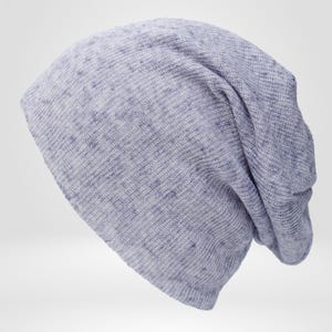 May include: A light blue beanie hat with a loose, slouchy fit. The hat is made of a soft, knit fabric with a speckled pattern. The beanie is designed to be worn casually and provides warmth.