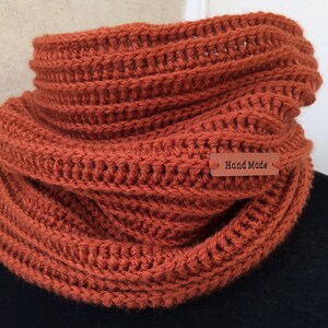 May include: A rust-colored crocheted neck warmer with a brown leather tag that says "Hand Made".