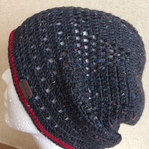 May include: Gray crocheted beanie with a red trim and a brown leather tag that says "Crochet Friends".