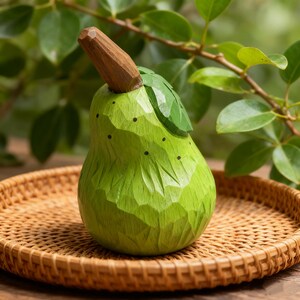 Peut inclure: Une sculpture de poire en bois sculpt&eacute; &agrave; la main, peinte en vert avec une tige marron et une feuille verte. La poire a une surface textur&eacute;e et de petits points noirs. Elle repose sur un plateau en osier tress&eacute;, avec un feuillage vert en arri&egrave;re-plan.