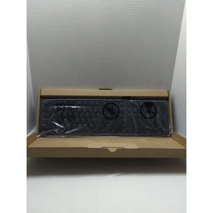 Könnte beinhalten: Eine schwarze Computertastatur in einem Karton. Die Tastatur ist in durchsichtige Folie eingewickelt. Die Box ist geöffnet und zeigt die Tastatur und ihre Verpackung. Der Hintergrund ist weiß.